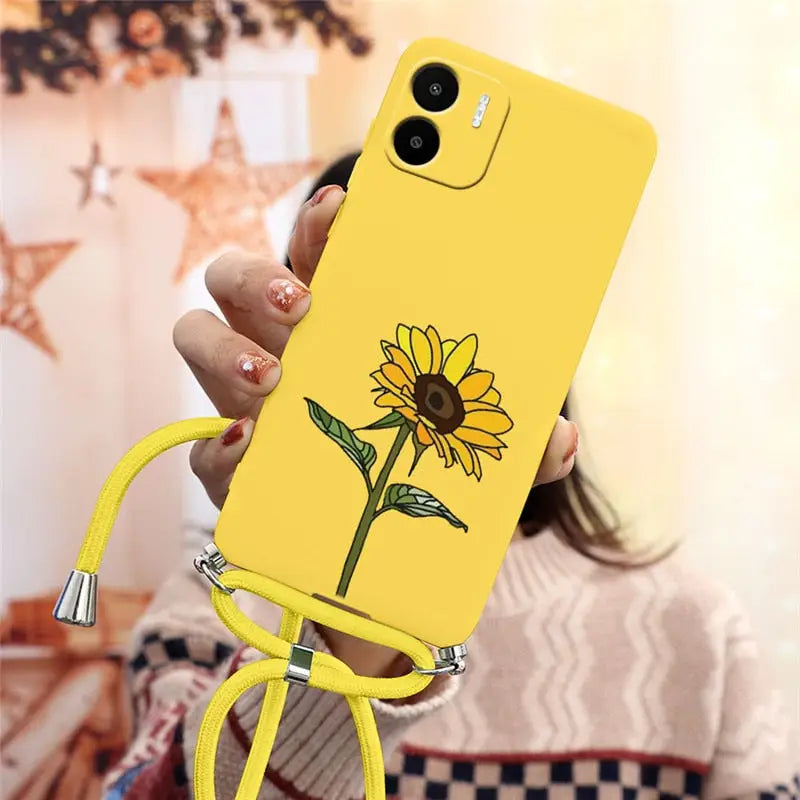 a woman holding a yellow phone case with a flower