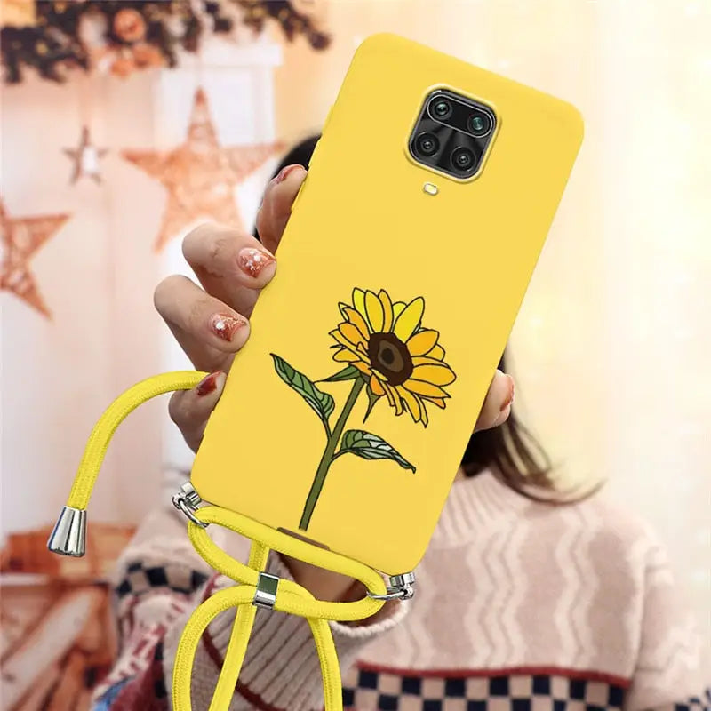 a woman holding a yellow phone case with a flower