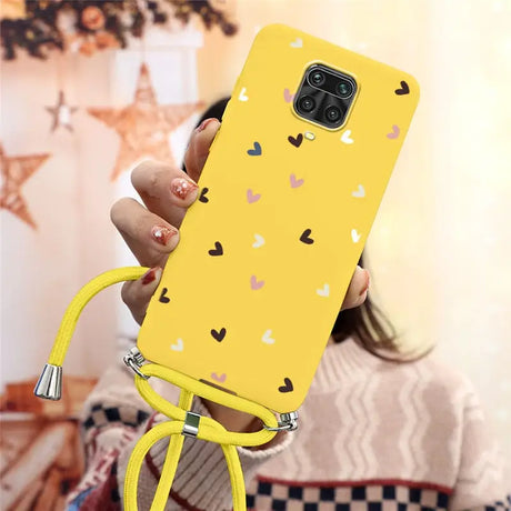 a woman holding a yellow phone case with hearts on it