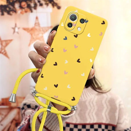 a woman holding a yellow phone case with hearts on it