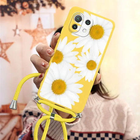 a woman holding a yellow phone case with white flowers on it