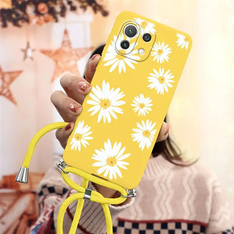 a woman holding a yellow phone case with white flowers on it