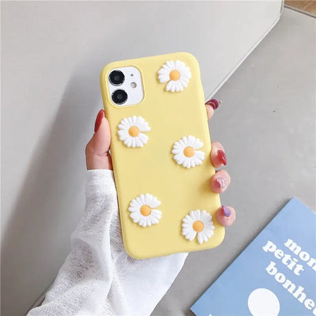 a woman holding a yellow phone case with white flowers on it