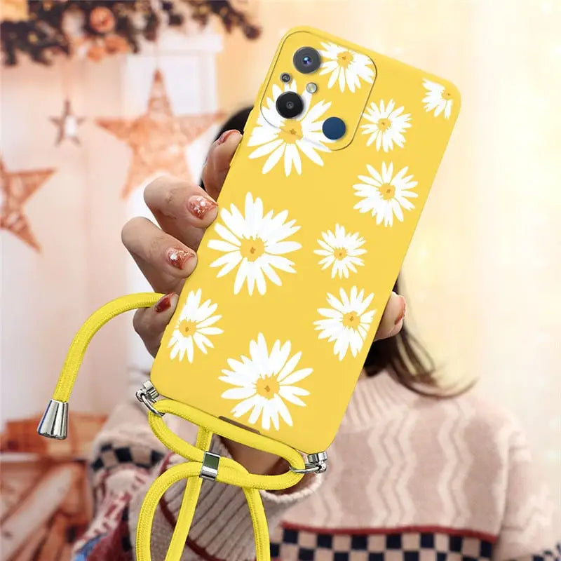 a woman holding a yellow phone case with white flowers on it