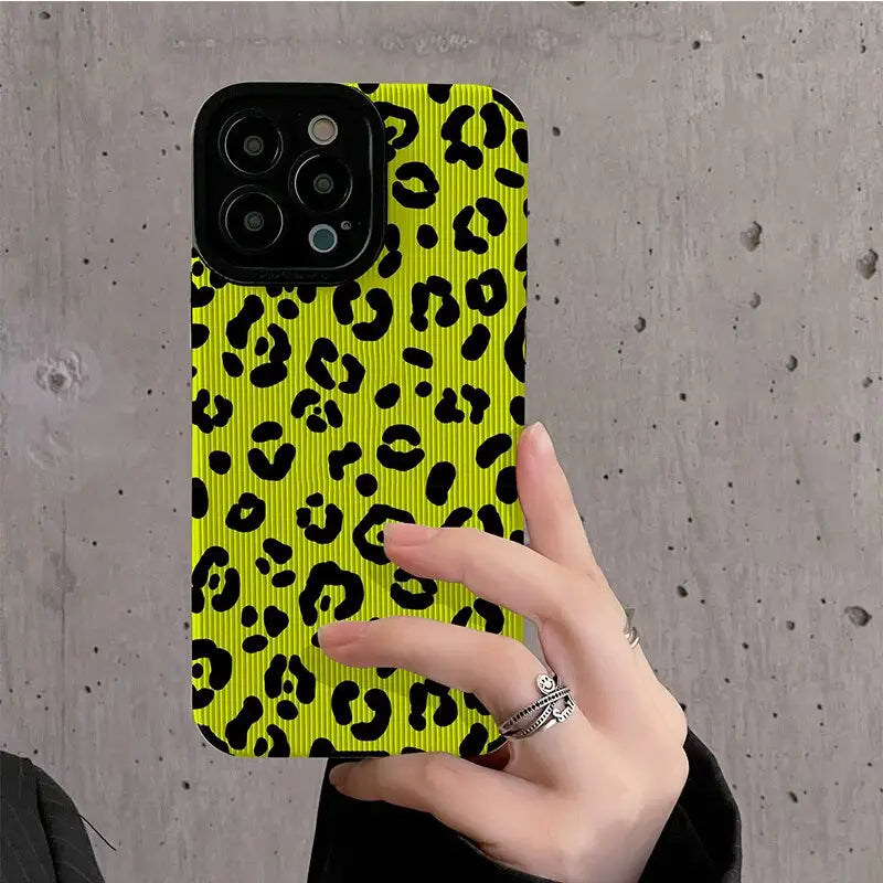 a woman holding a yellow phone case with black and yellow leopard print