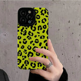 a woman holding a yellow phone case with black and yellow leopard print