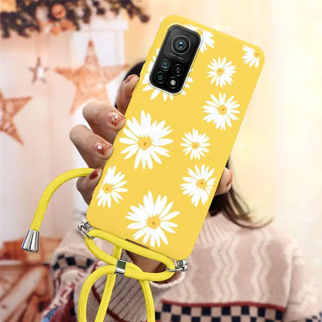 a woman holding a yellow phone case with white flowers on it