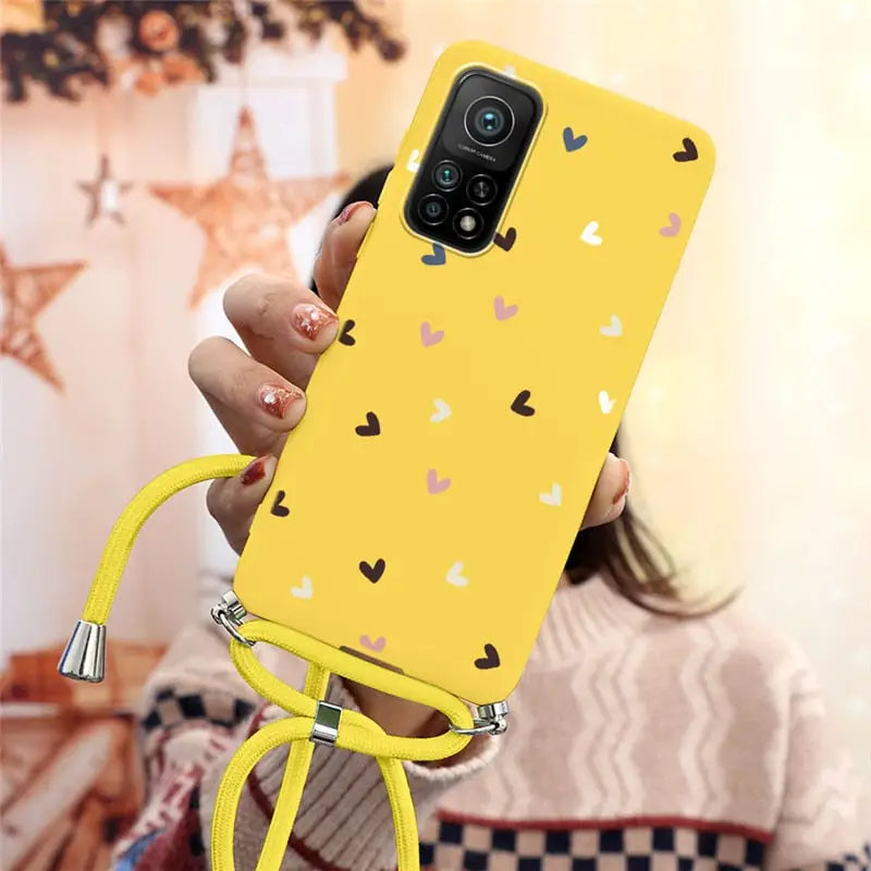 a woman holding a yellow phone case with hearts on it