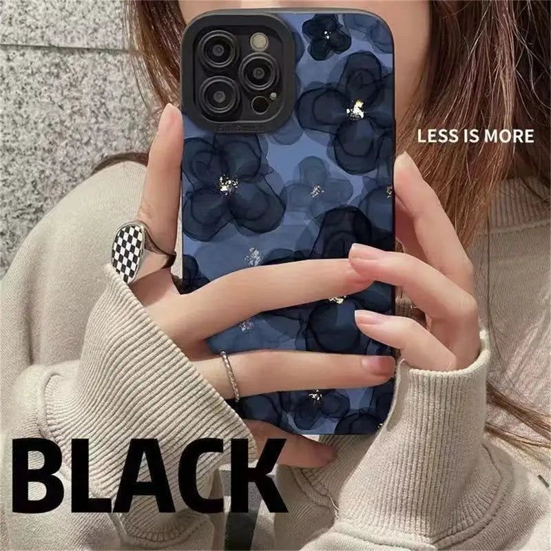 a woman holding a phone case with a black flower pattern