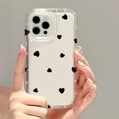 A woman holding a phone case with black hearts on it