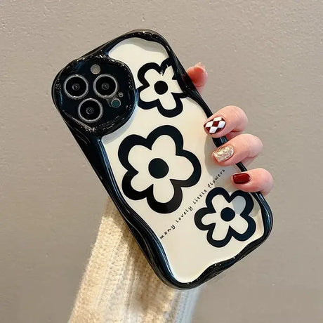 A woman holding a phone case with a black and white pattern