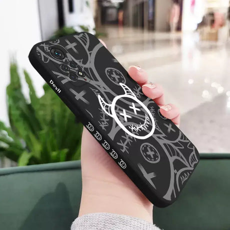 A woman holding a phone case with a black and white design