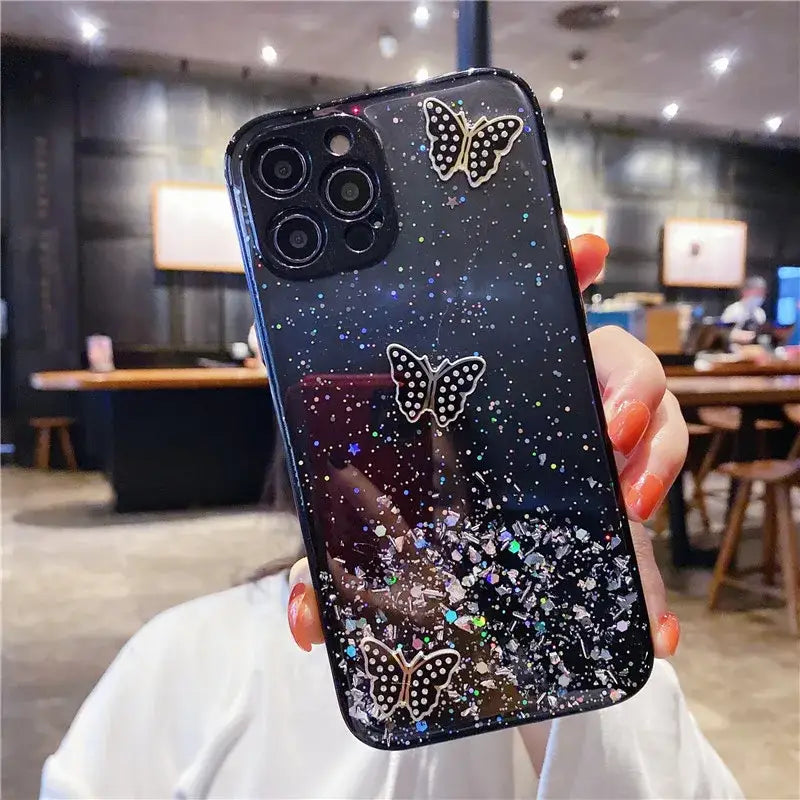 a woman holding up a phone case with a black and white glitter design