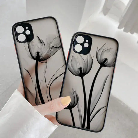 A woman holding a phone case with a black and white flower design