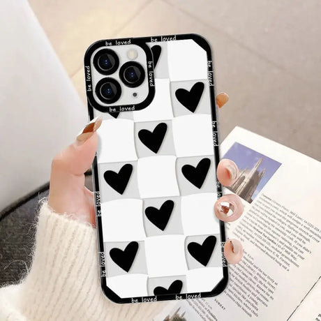 a woman holding a phone case with black hearts on it