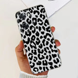 a woman holding a phone case with a black and white leopard print