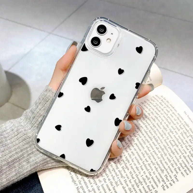 a woman holding a phone case with black hearts on it