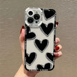 A woman holding a phone case with black and white hearts