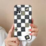 a woman holding a phone case with a black and white checkered pattern