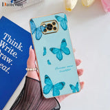 a woman holding a phone case with blue butterflies on it