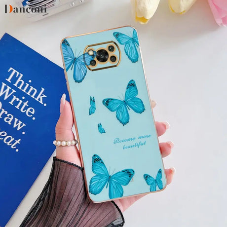 a woman holding a phone case with blue butterflies on it