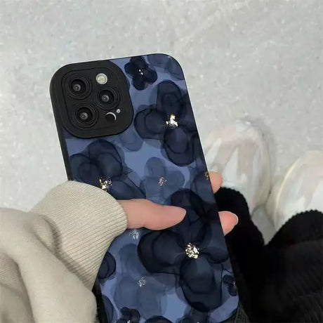 A woman holding a phone case with a blue floral pattern