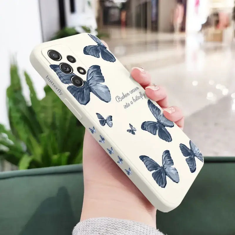a woman holding a phone case with blue butterflies on it