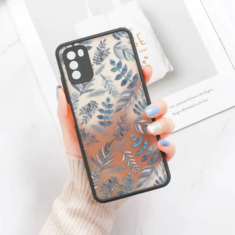 A woman holding a phone case with blue leaves on it