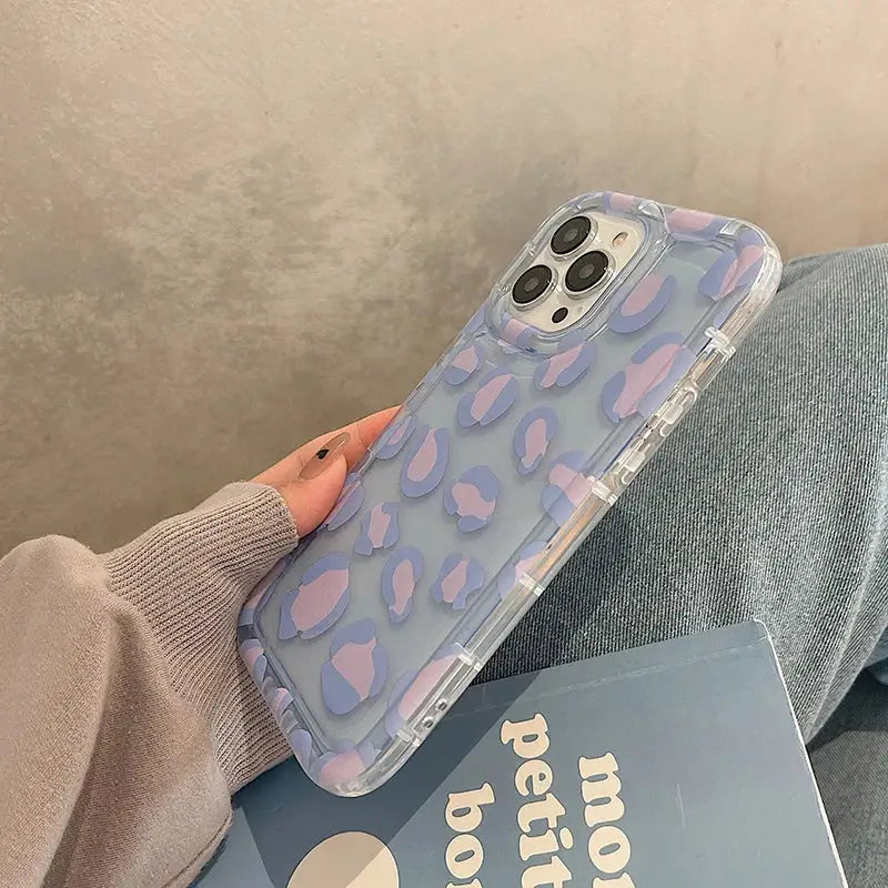 a woman holding a phone case with a blue and purple camouflage print