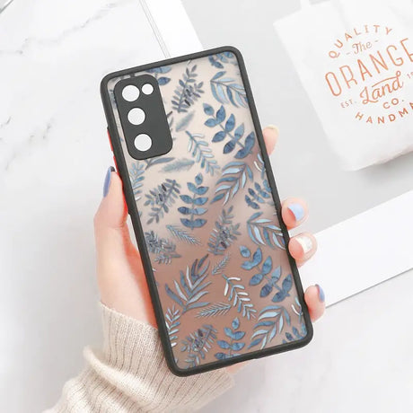 A woman holding a phone case with blue leaves on it