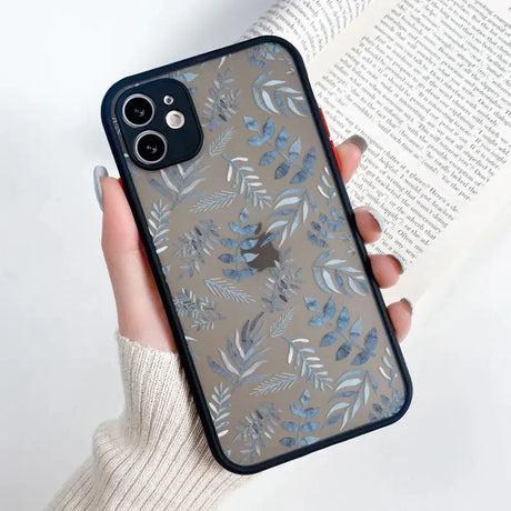 A woman holding a phone case with blue leaves on it