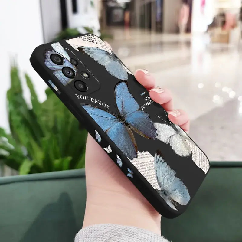 a woman holding a phone case with a blue butterfly on it