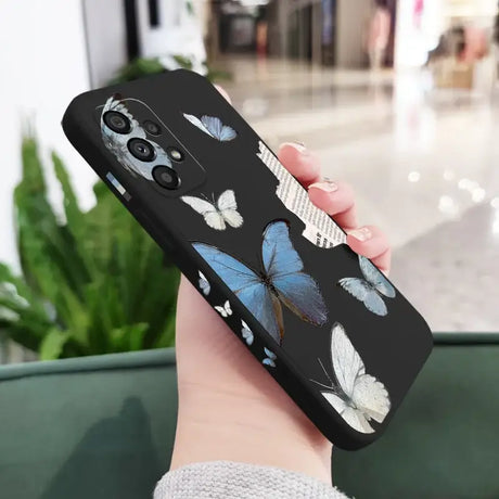 A woman holding a phone case with a blue butterfly on it