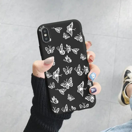 A woman holding a phone case with butterflies on it