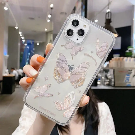 A woman holding up a phone case with butterflies on it