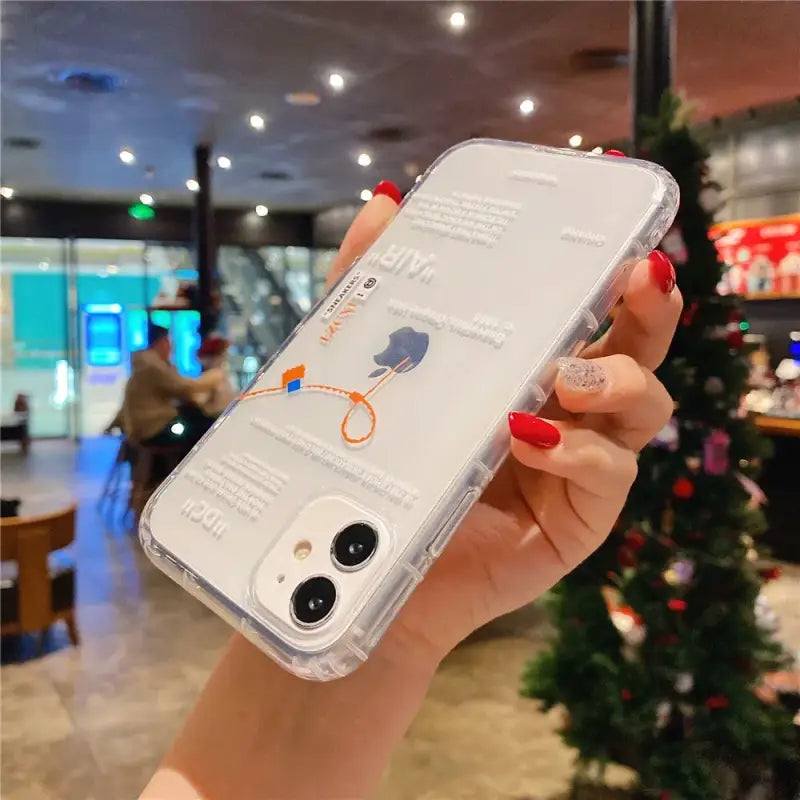 a woman holding up a phone case with a christmas tree in the background