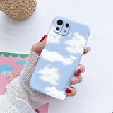 a woman holding a phone case with clouds in the sky