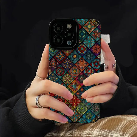 A woman holding a phone case with colorful patterns