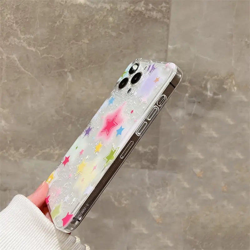 a woman holding a phone case with a colorful star pattern
