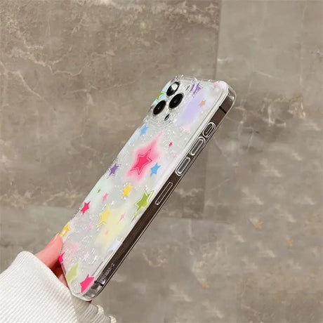 A woman holding a phone case with a colorful star pattern