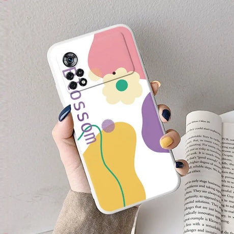 A woman holding a phone case with a colorful flower on it