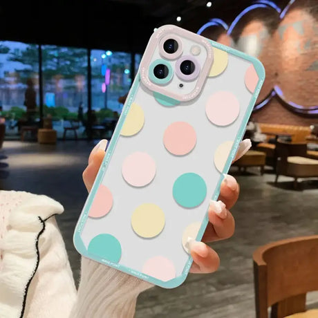 A woman holding up a phone case with colorful polka dots