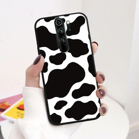 A woman holding a phone case with a cow print