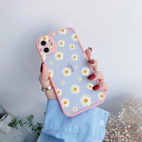 A woman holding a phone case with daisies on it