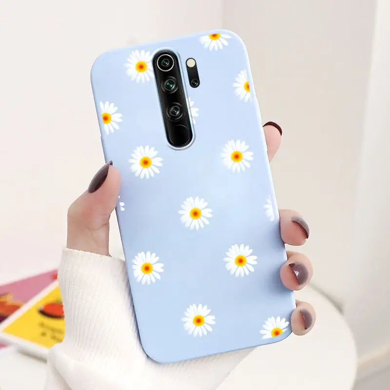 a woman holding a phone case with a daisy pattern on it