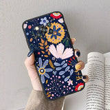 a woman holding a phone case with a floral pattern