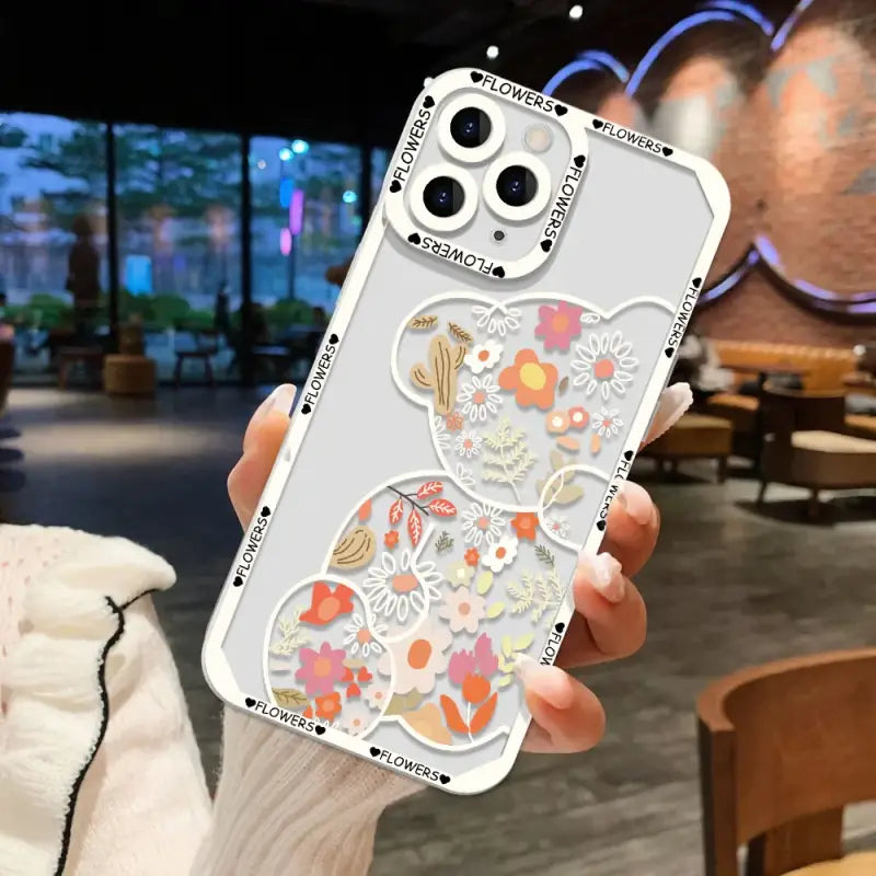 a woman holding up a phone case with a floral design