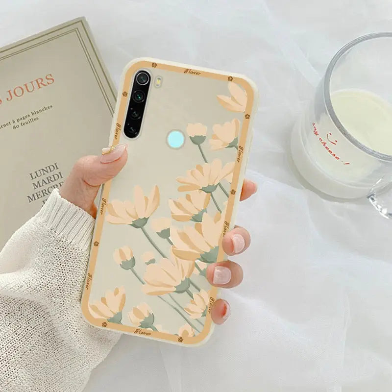 a woman holding a phone case with flowers on it