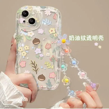 a woman holding a phone case with flowers and leaves