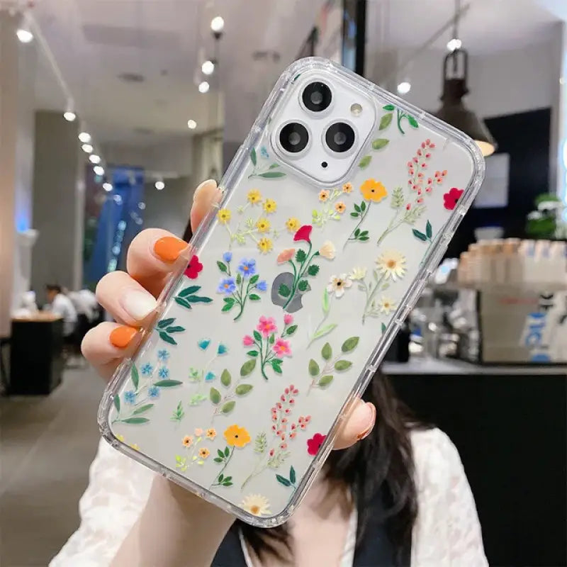 A woman holding up a phone case with flowers on it